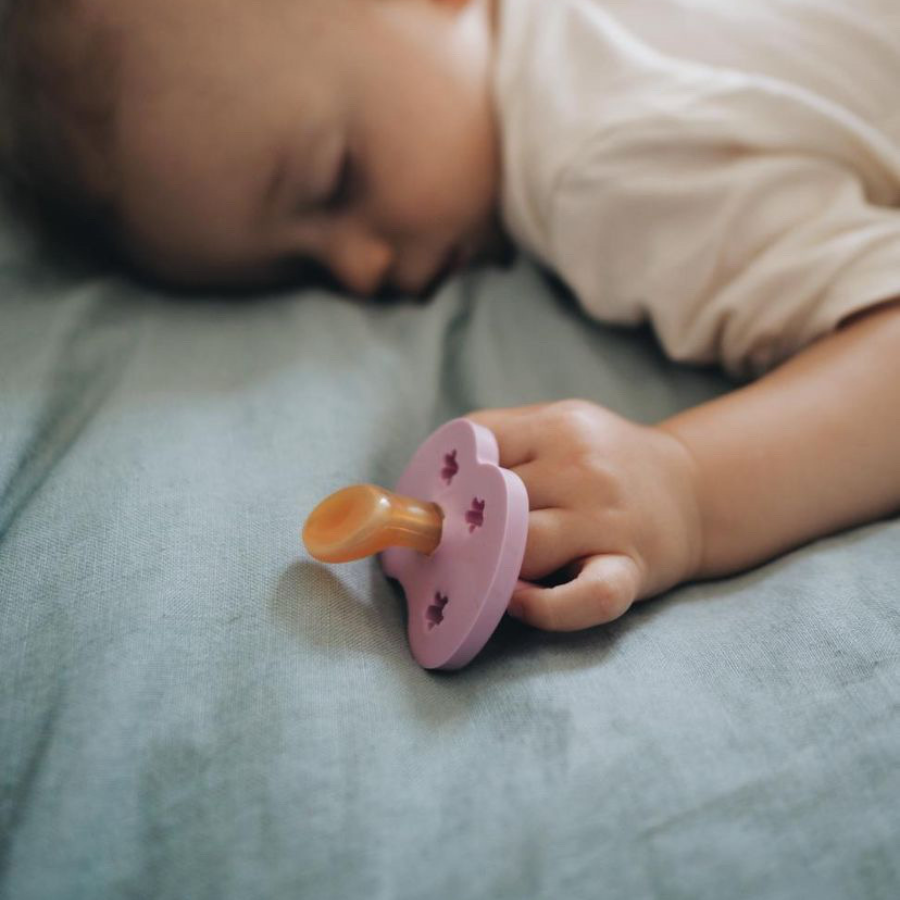 Baby schläft mit ortodontisch Geformten Naturkautschuk-Schnuller von Hevea in der Hand, natürliche Schnuller kaufen bei GREEN &amp; GROW