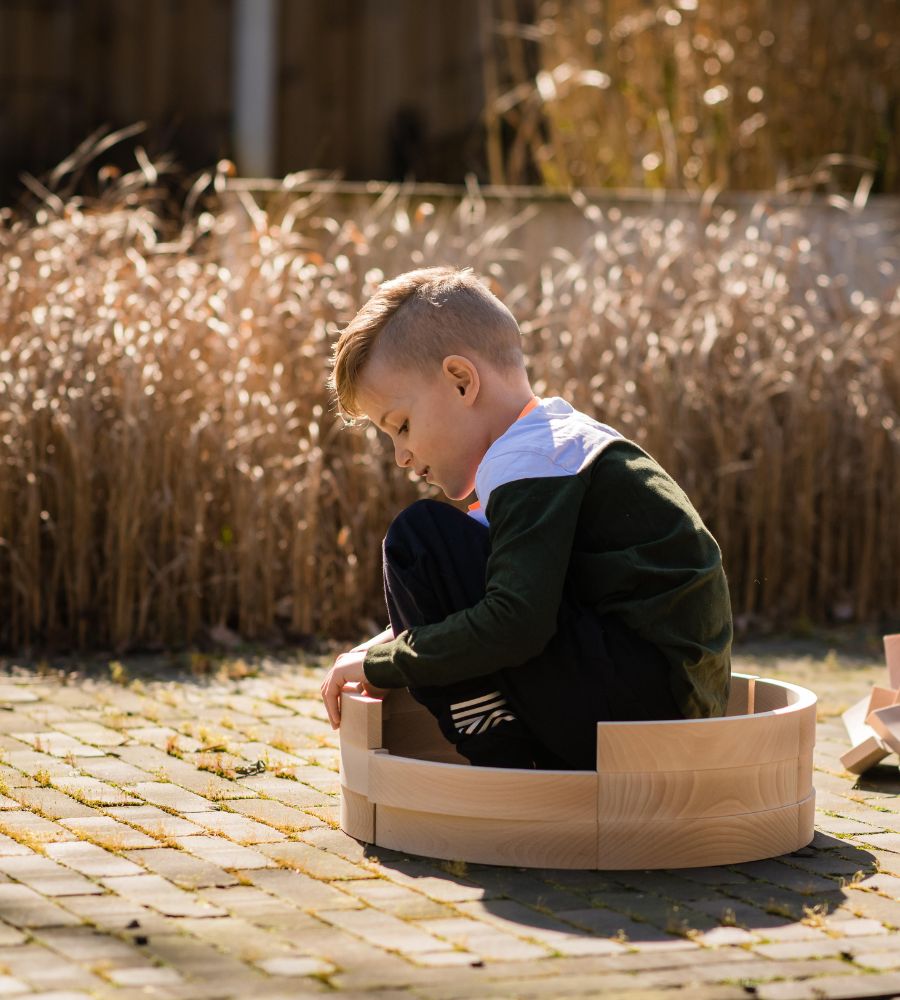 Kind spielt in herbstlichem garten mit bio holzbausteinen von abel blocks